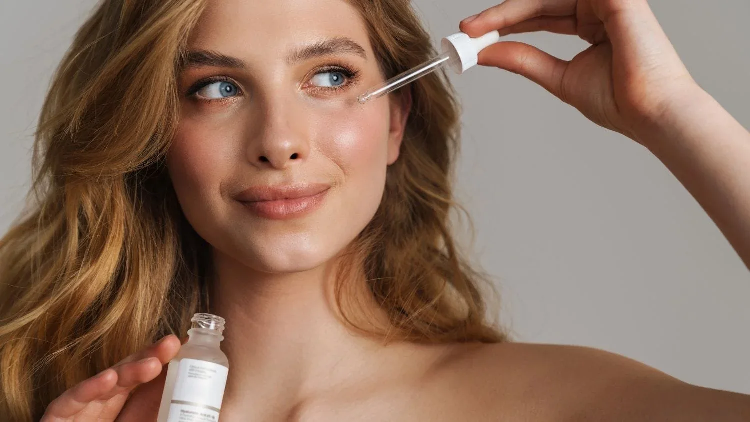 Woman applying a serum drop to her cheek